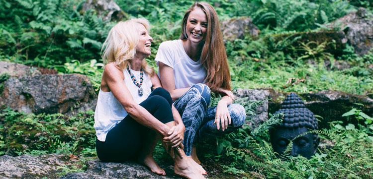 Kelly Childs and Erinn Weatherbie on vacation sitting in a forest smiling