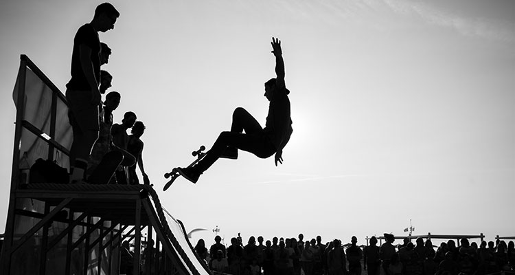 A skateboarder making a jump at the top of a half pipe.
