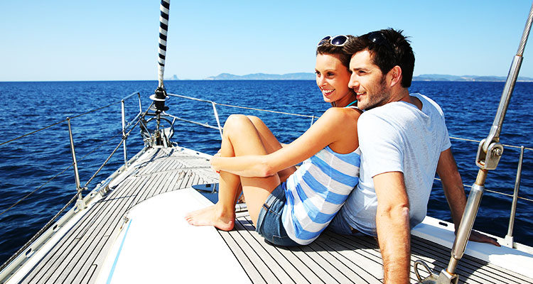 A couple on a sailboart with mountain islands in the background