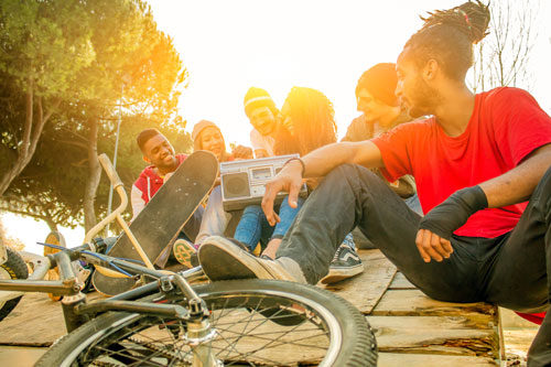 Group of friends sitting with the bikes and skateboards.