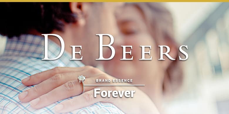 De Beers brand essence is forever. Woman with diamond ring hugging a man.