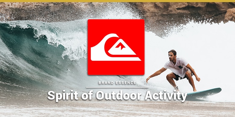 Quiksilver's brand essence is spirit of outdoor activity. Man surfing on rocky beach.