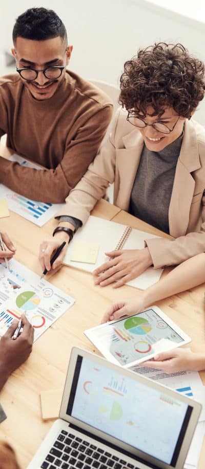 Man and woman having a meeting at a board room table talking about graphs and figures.