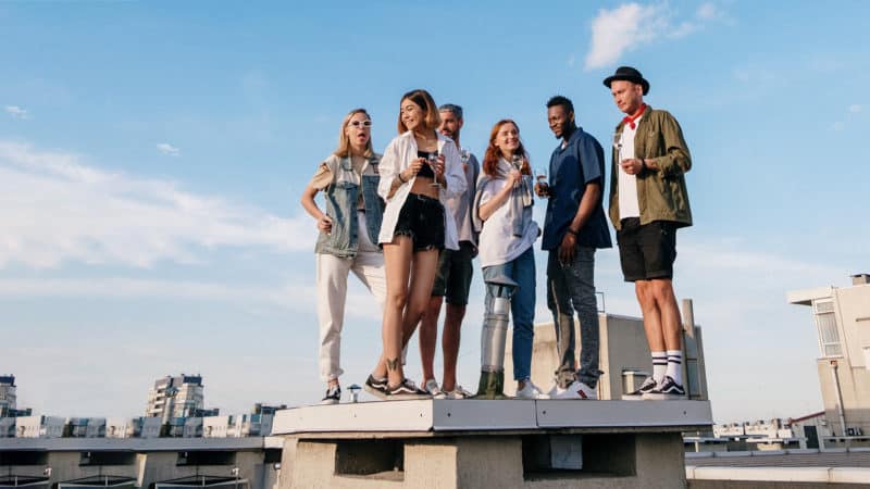 Teens on a roof looking at the view because of peer influence.