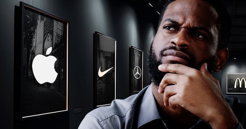 Man with an enquisitive look in a gallery with logos of Apple, Nike, Mercedes and McDonalds.