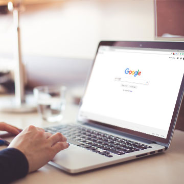 Woman typing a search into Google onto a laptop