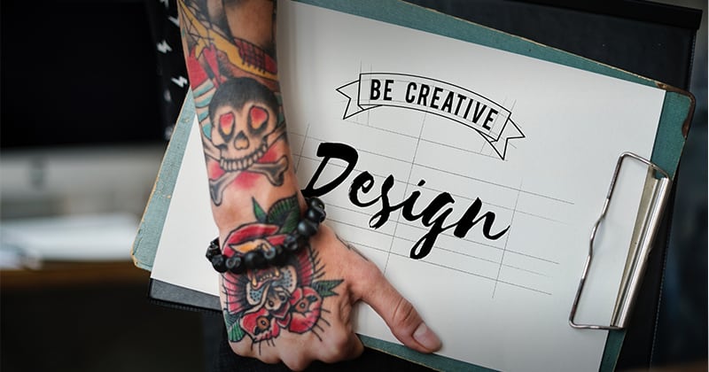 Tattooed arm holding design. Design says "be Creative: design"