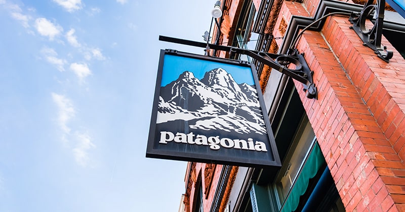 Wood cut sign for Patagonia on the outside of a brick building.