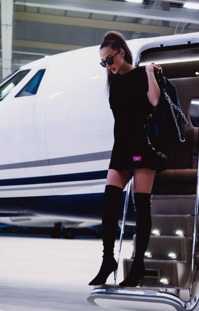 Celebrity exiting a private jet in designer clothes with a designer handbag.