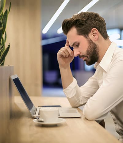 Brand marketer looking concerned leaning over his desk looking at his computer.